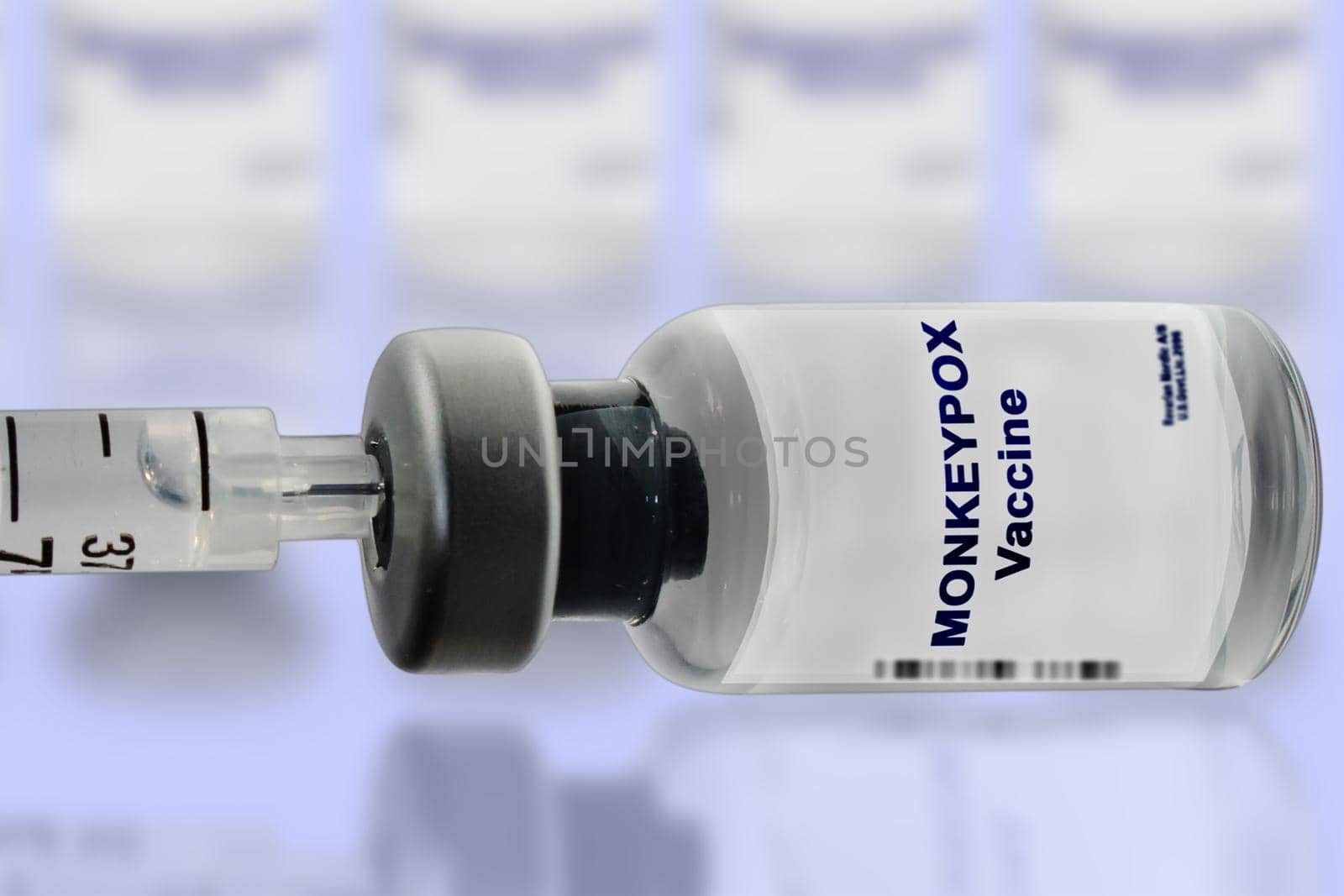 Monkeypox vaccine with a syringe close-up on a light background. Blurred vaccine vials in the background.