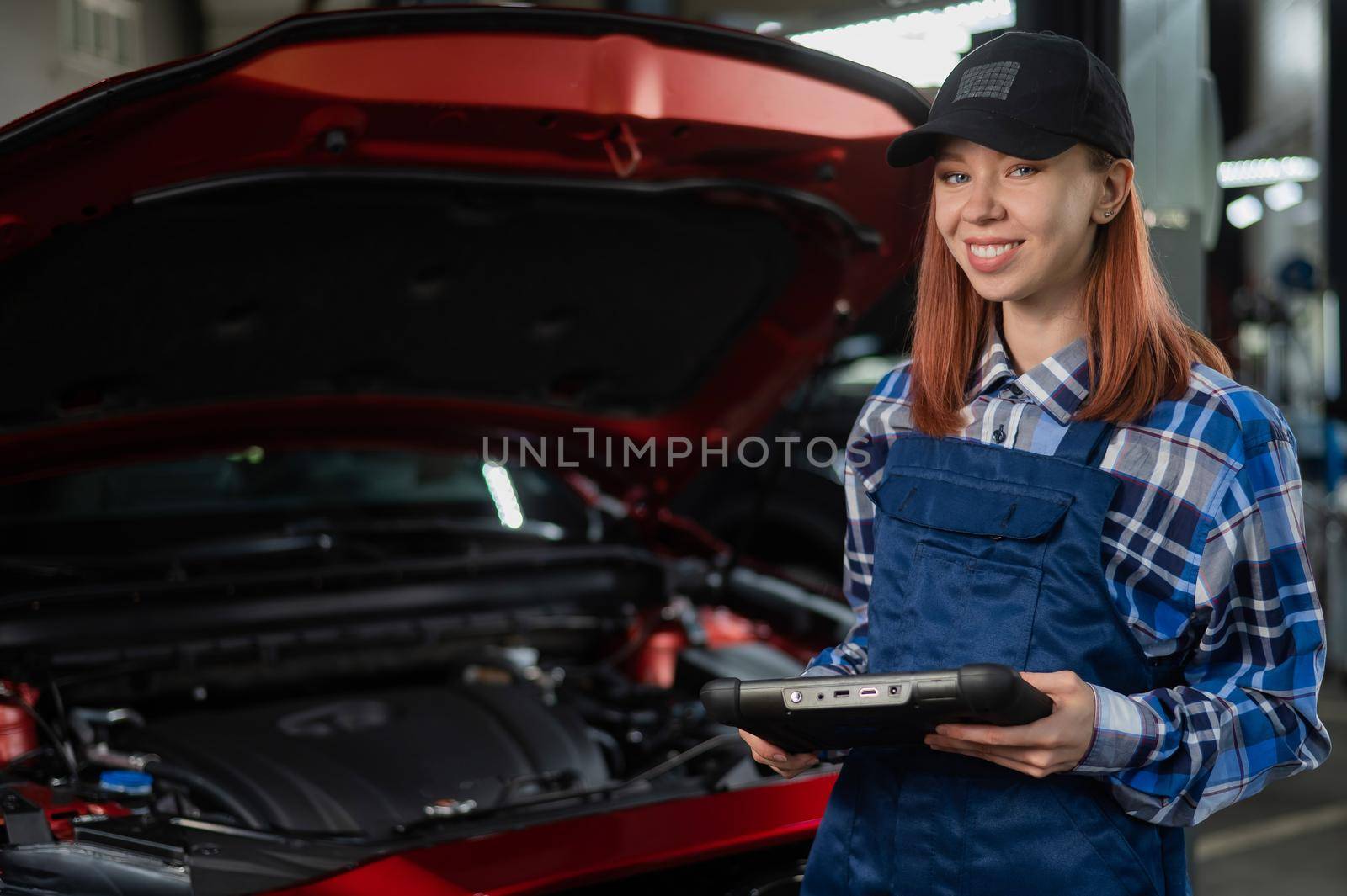 Caucasian female auto mechanic uses a special computer to diagnose faults