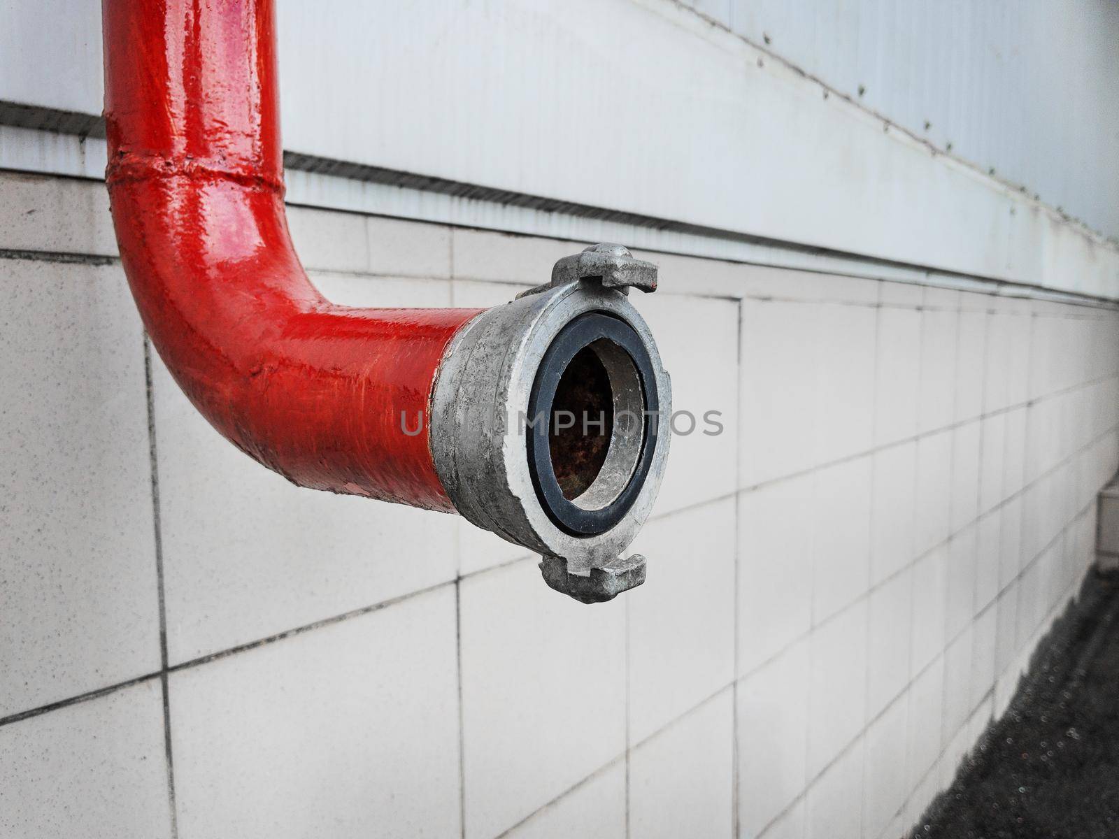Red fire-fighting pipeline with a lock close-up on a tile background