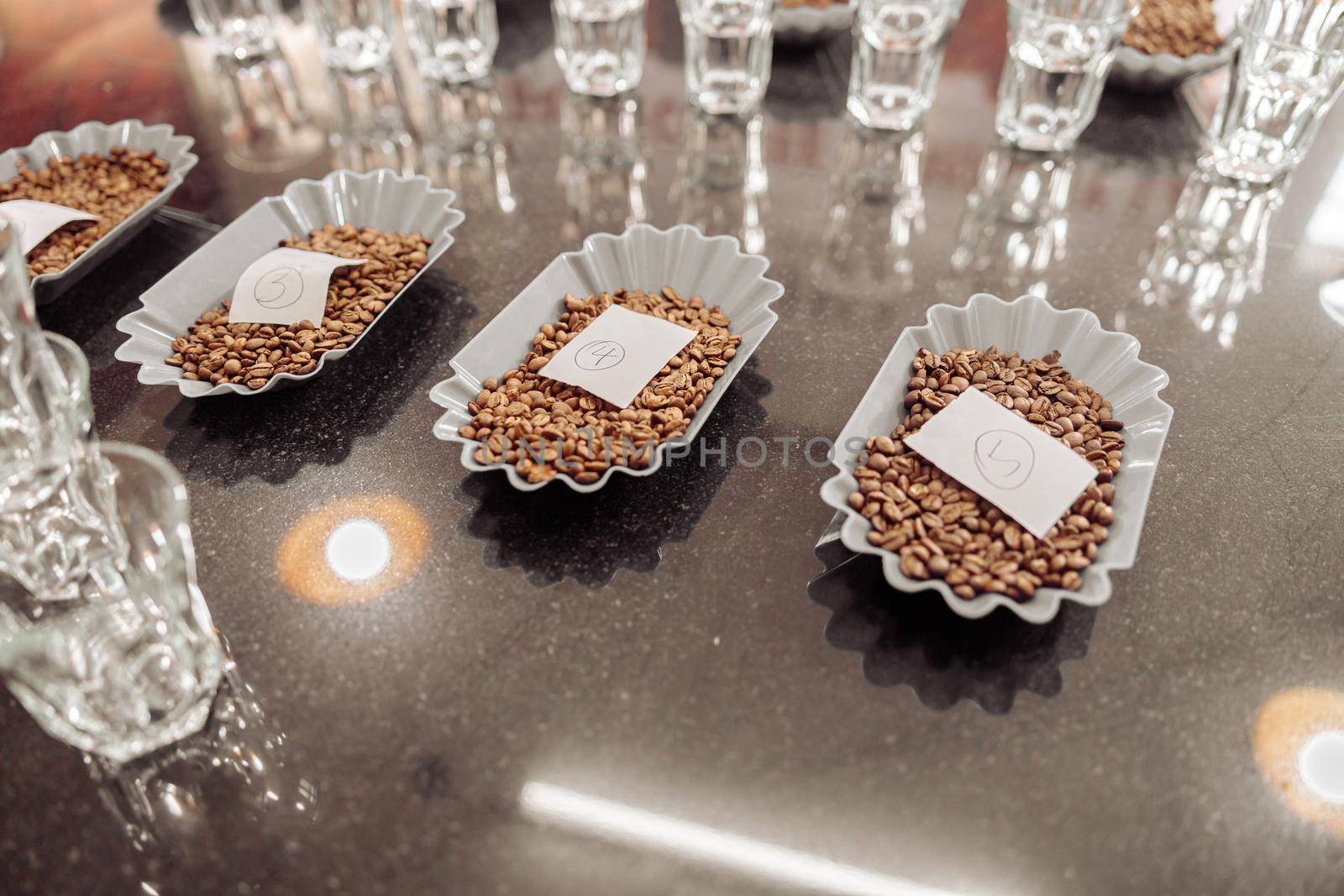 Top view of empty water glasses and bowls with coffee beans and notes on the table for tasting