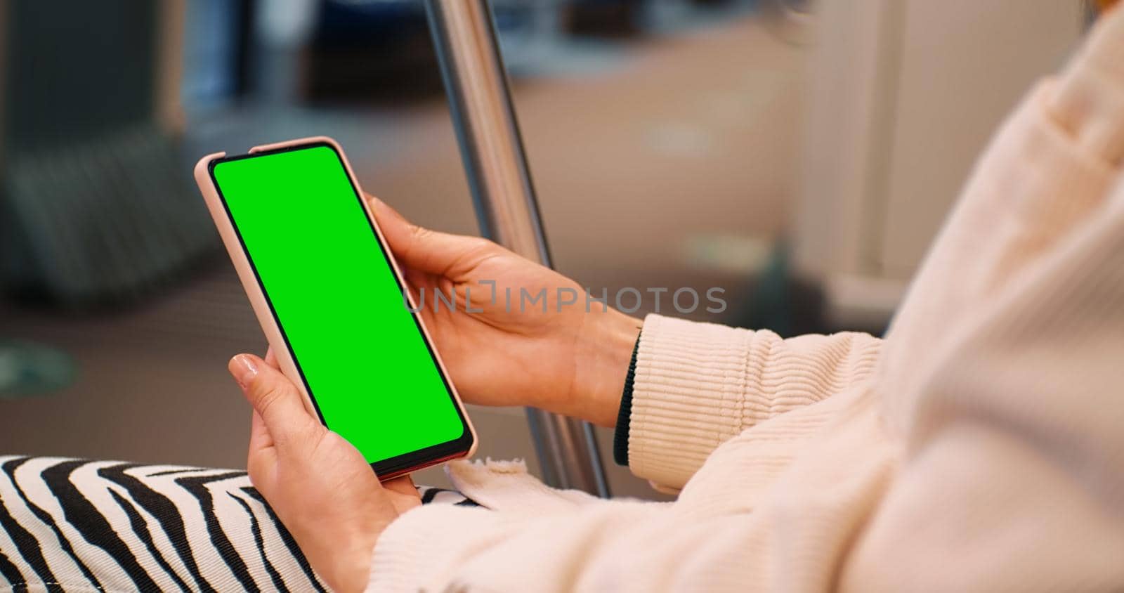 Female hands using Smartphone with Green Screen Mock Up Display on subway. Woman watching on the phone on the underground. Technology in life.