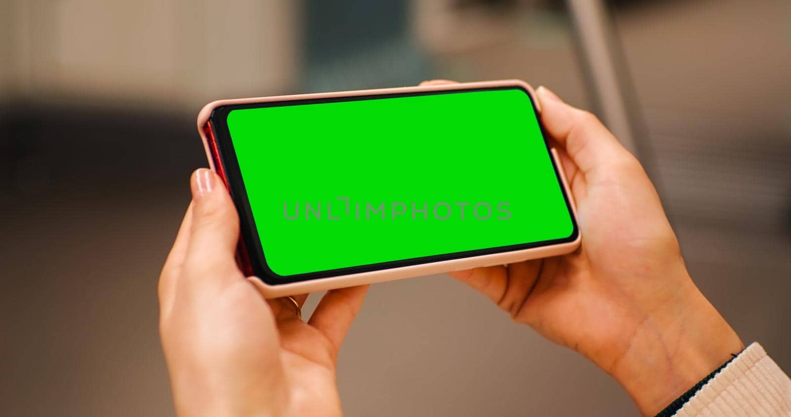 Close-up woman hands watching on the horizontal green screen phone on train, transport. Green screen cromakey phone used by woman on subway. Technology lifestyle.