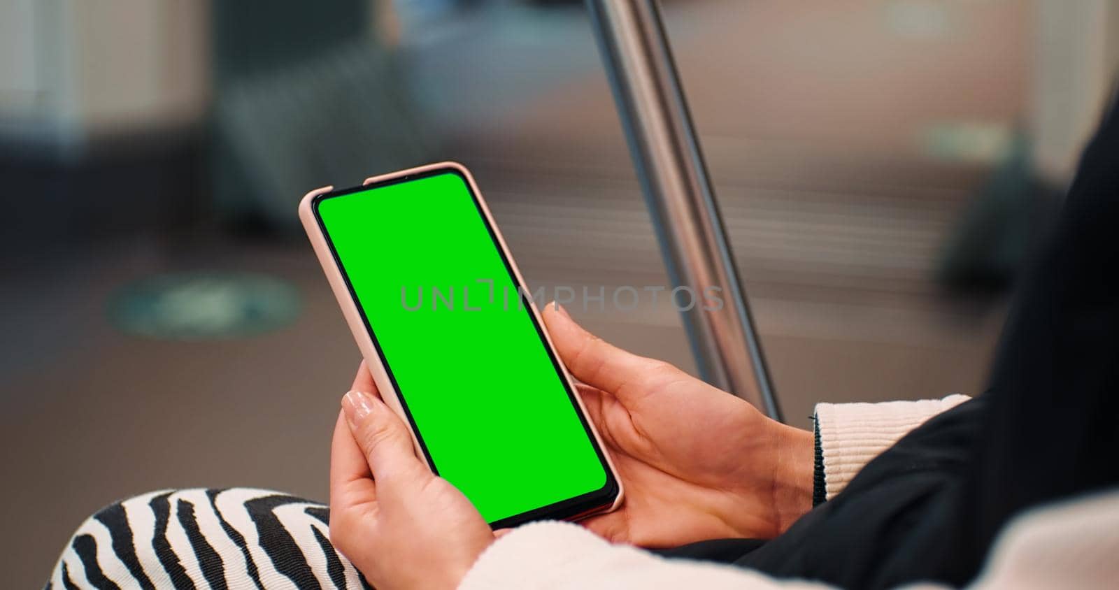 Woman hands close up watching on the phone on green screen, chromakey. Female hands using cellphone on subway. Technology content.