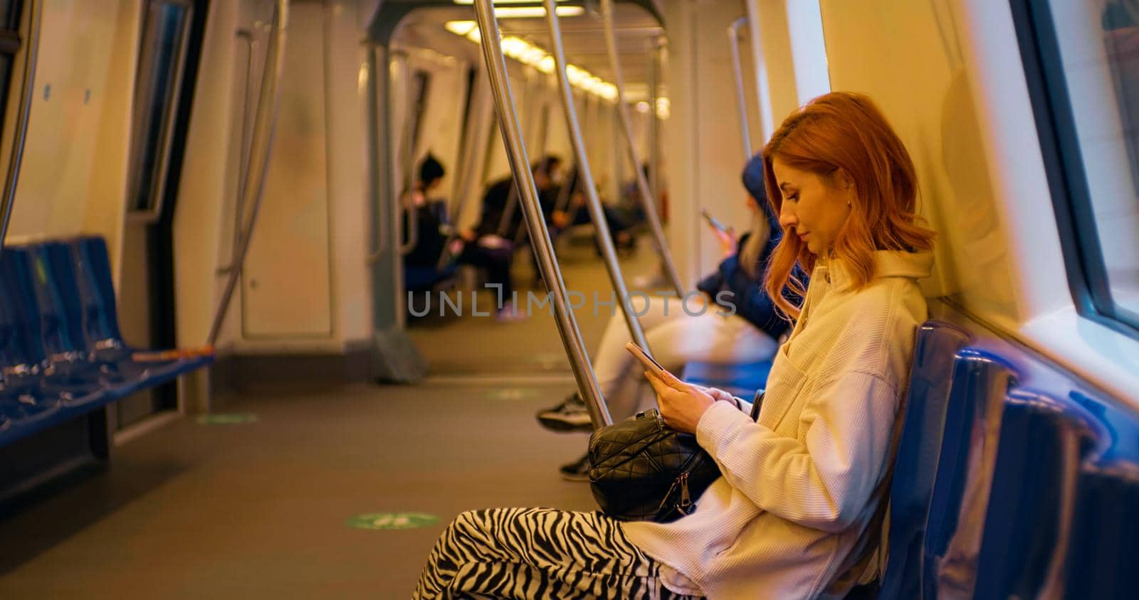 Woman reading on smartphone screen, standing in public transport. Female surfing for information. Internet addiction.