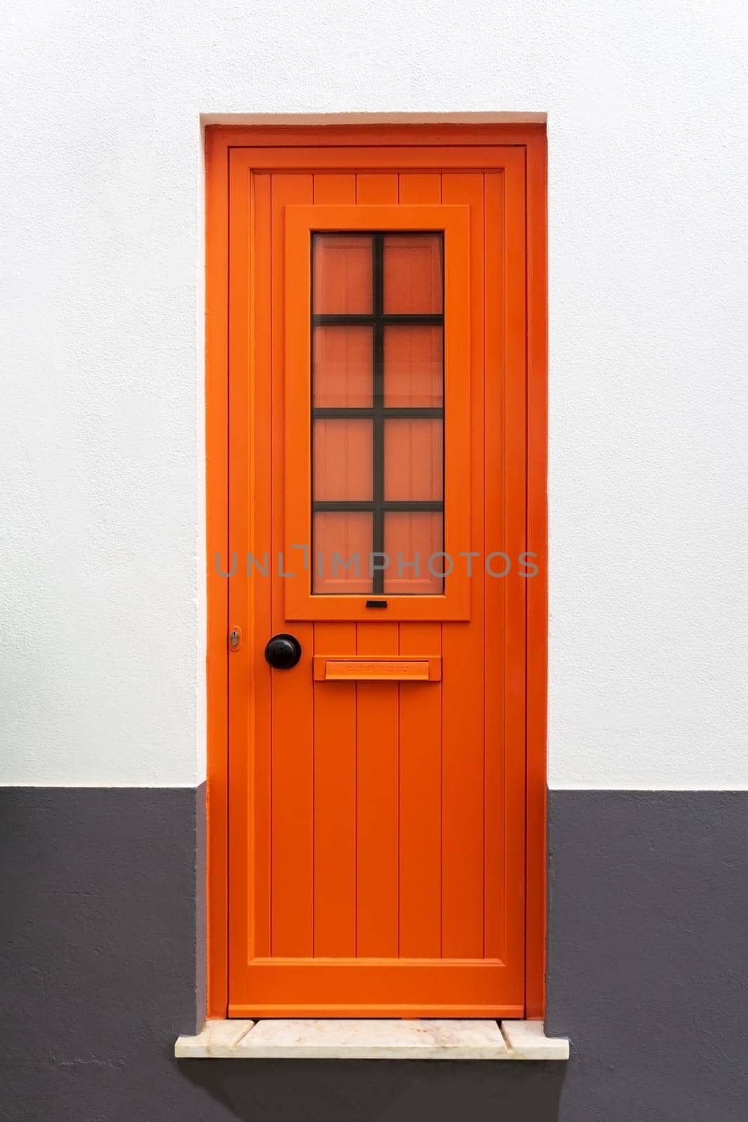 New closed modern bright orange door in a white - gray wall