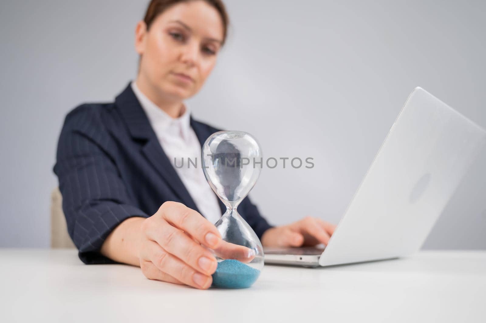 Business woman flipping an hourglass at her desk