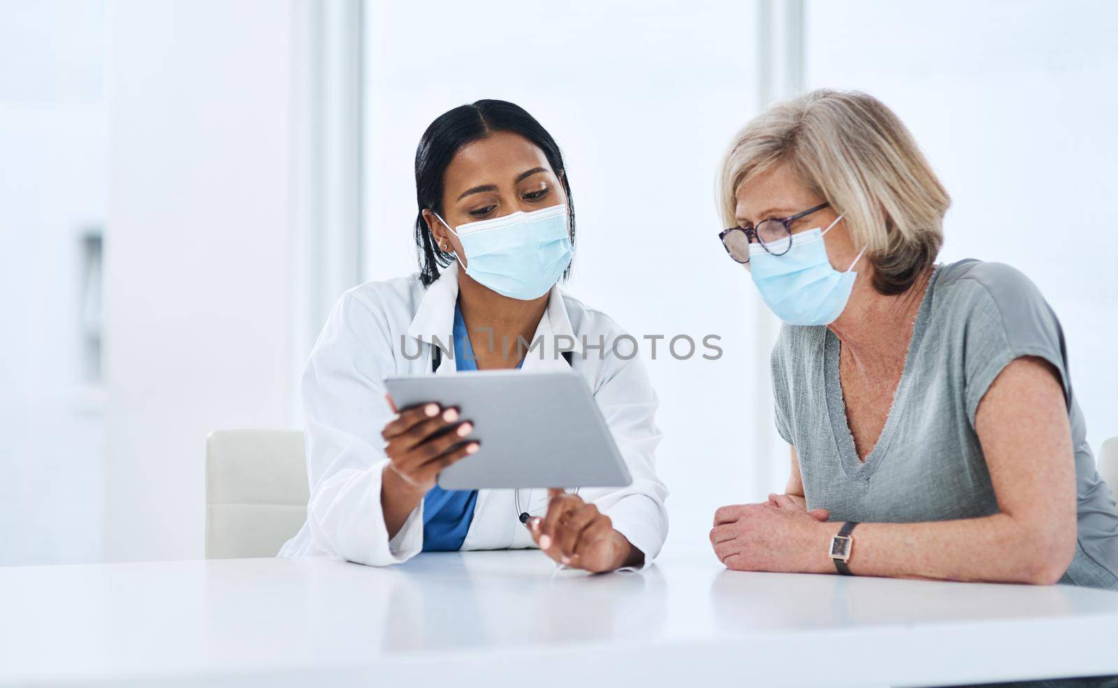 Expert diagnosis that patients can depend on. a young doctor using a digital tablet during a consultation with a senior woman. by YuriArcurs