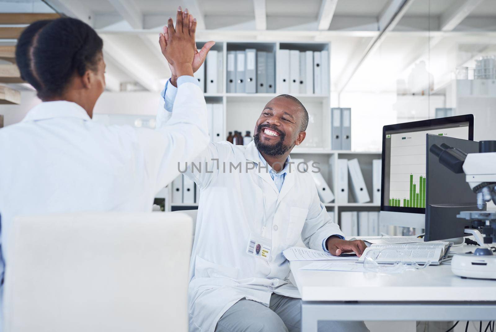 I scream, you scream, we all scream for science. two scientists giving each other a high five while conducting research in a laboratory. by YuriArcurs