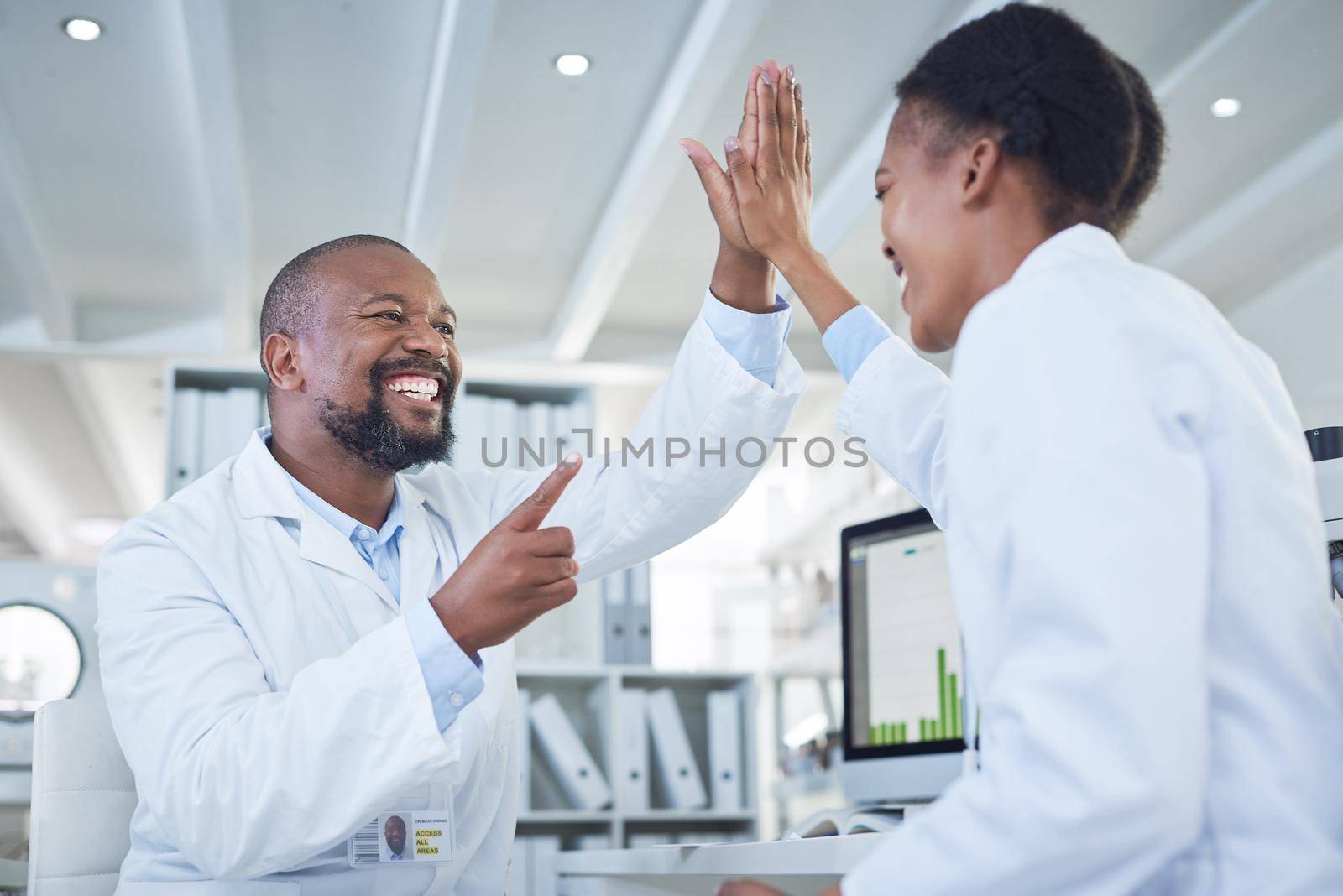 Science saves the day. two scientists giving each other a high five while conducting research in a laboratory. by YuriArcurs
