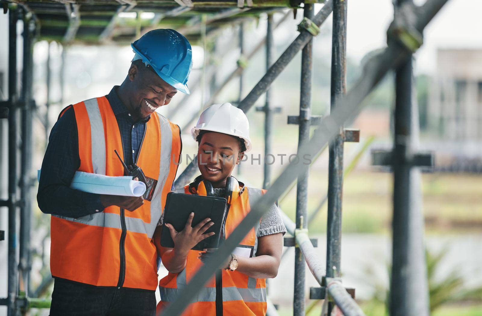 Collecting, storing and tracking all building compliance documentation. a young man and woman using a digital tablet while working at a construction site. by YuriArcurs