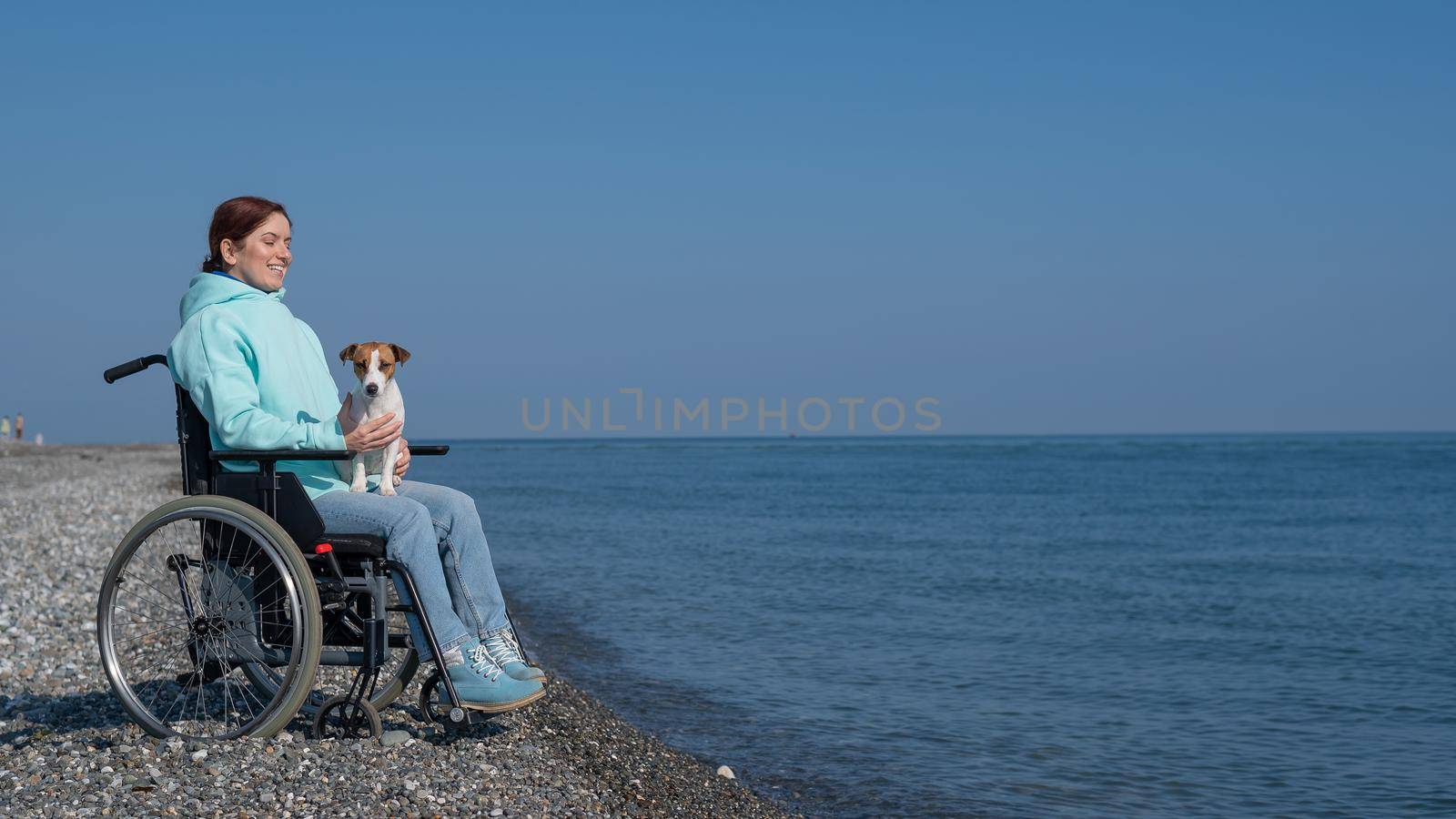 Caucasian woman in a wheelchair with a dog at the sea