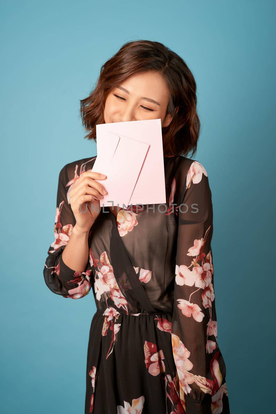Young beautiful woman reading a love letter over light blue background