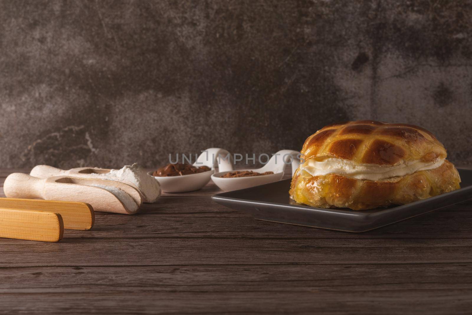 cream-filled bun covered with sugar syrup on a grey plate on a wooden table