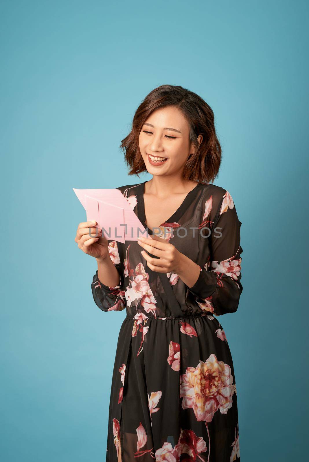 Young beautiful woman reading a love letter over light blue background by makidotvn