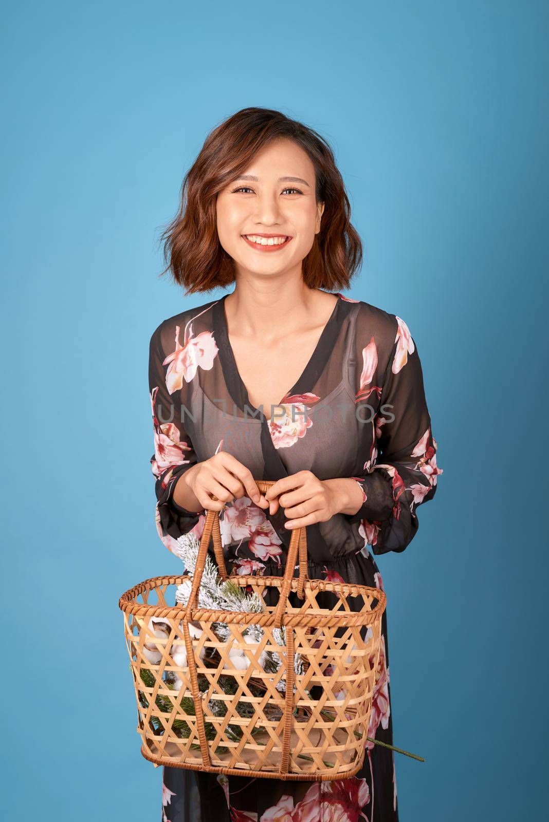 Beautiful young smiling woman in vintage dress holding a basket with flowers. Summer portrait pretty young girl.