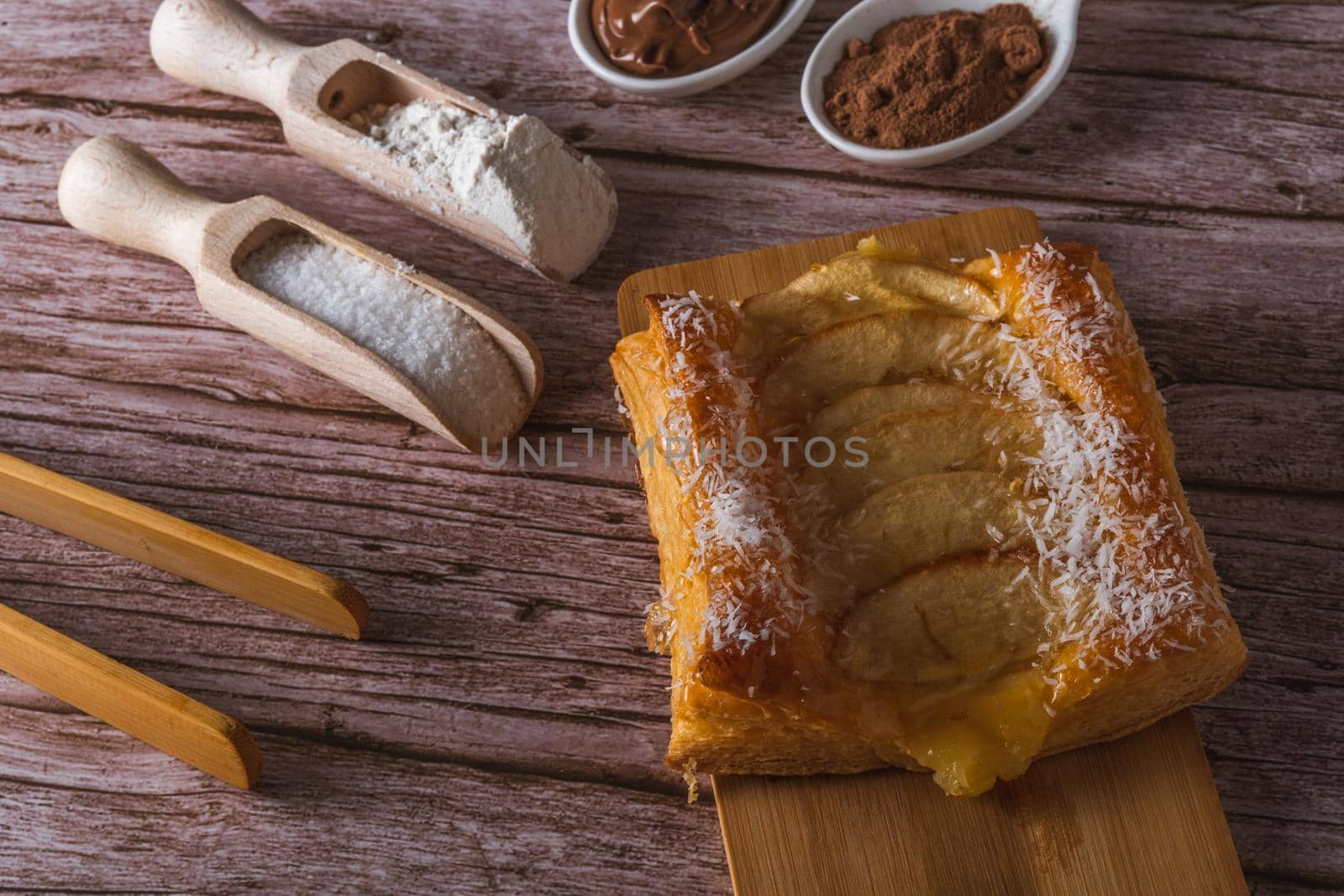 close-up of a chocolate-covered puff pastry with cream and almonds, on a white plate on a dark background