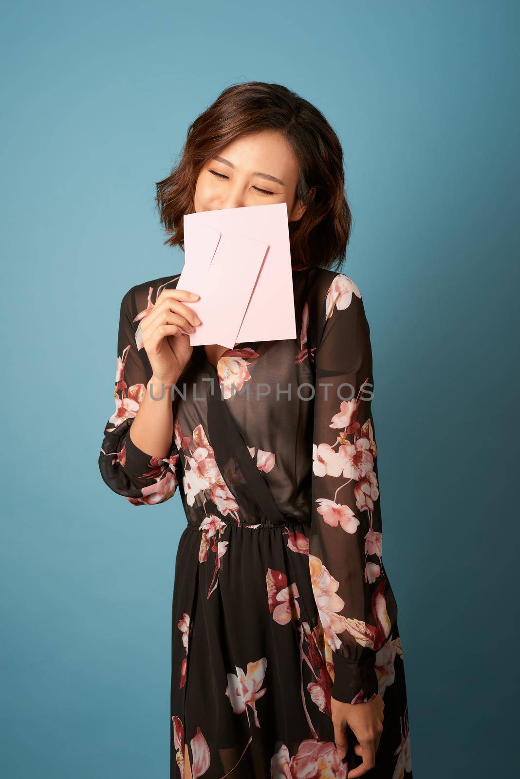 Young beautiful woman reading a love letter over light blue background