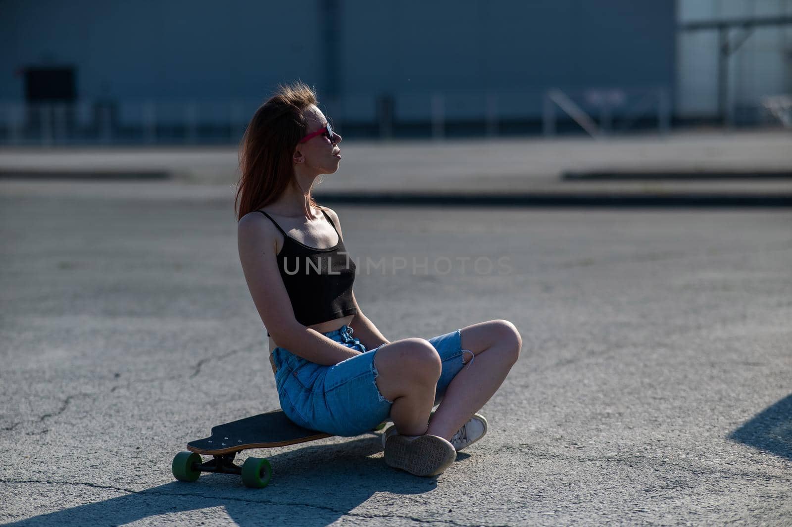 Young caucasian woman sitting on a longboard and relaxing outdoors