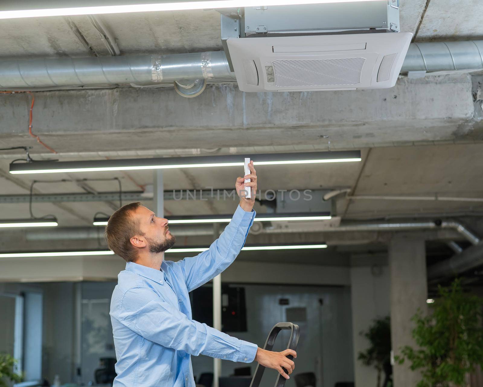 Caucasian bearded man repairing the air conditioner in the office. by mrwed54