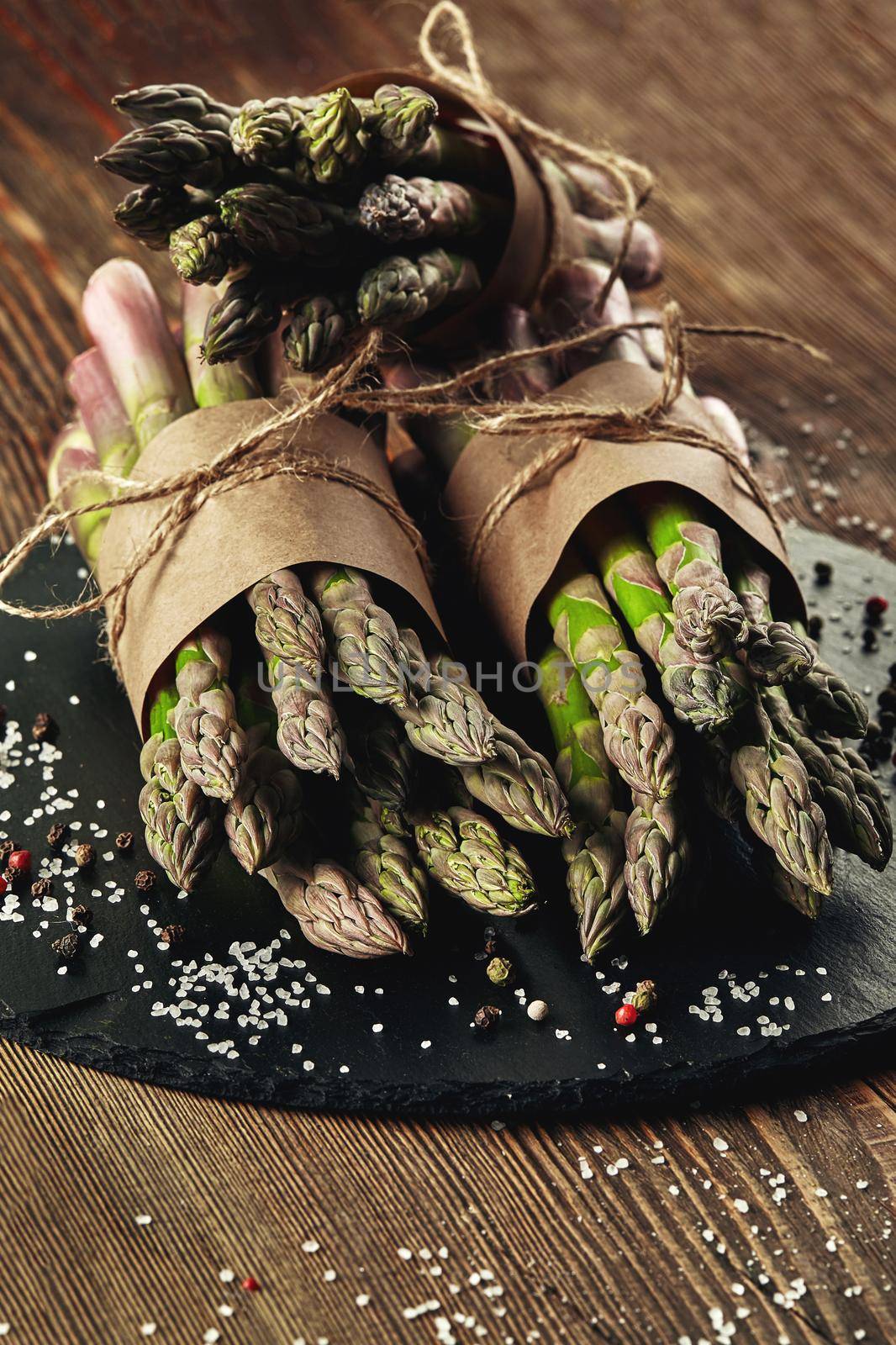 Bunches of an edible, organic stems of asparagus on wooden background. Fresh, green vegetables with seasonings. Healthy eating. Fall harvest, agricultural farming concept.