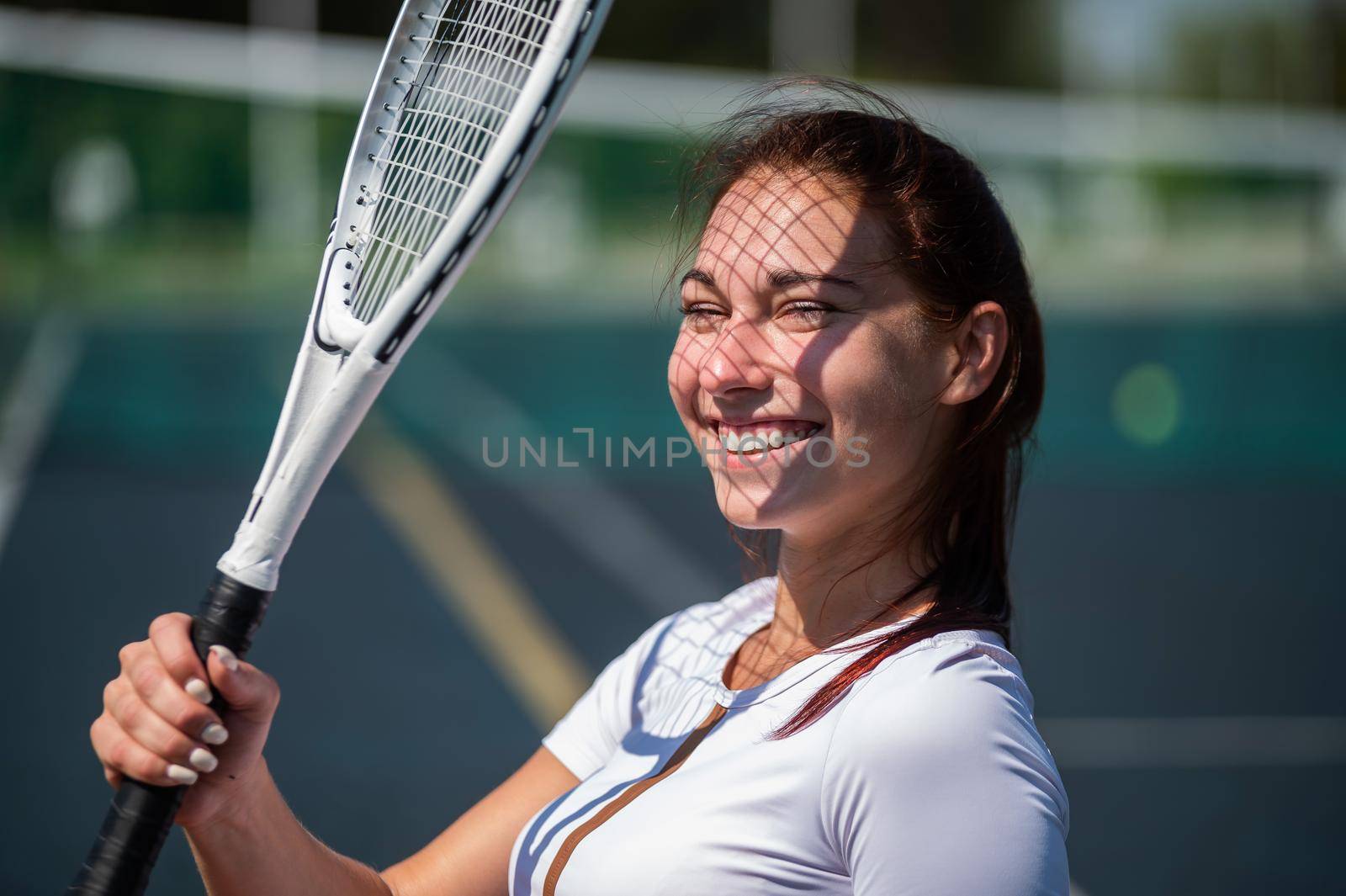 Beautiful smiling woman with a shadow from a tennis racket on her face on a sunny day.