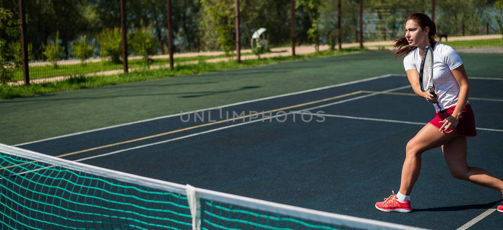 Sportive caucasian woman playing tennis on an outdoor court. Widescreen. by mrwed54