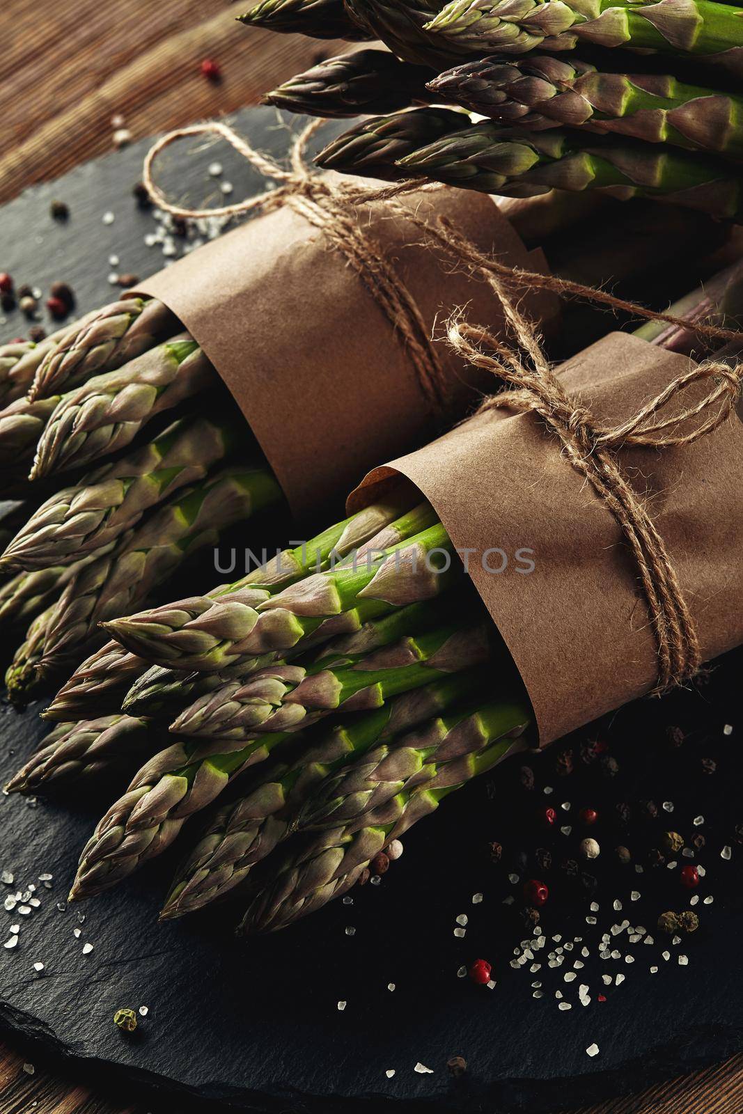 An edible, raw stems of asparagus on a wooden background. by nazarovsergey