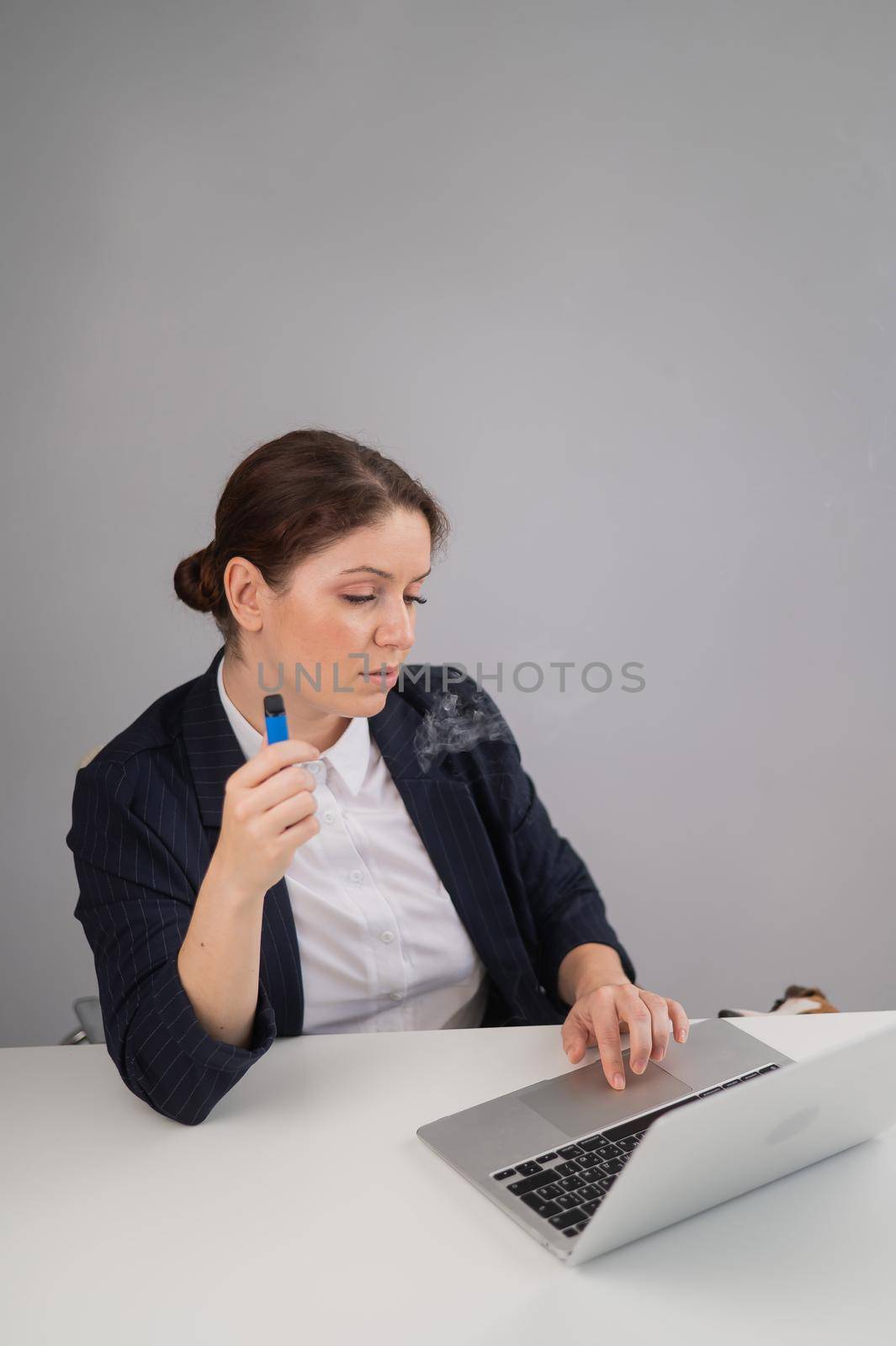 Business woman smoking a disposable vape while sitting at her desk. by mrwed54