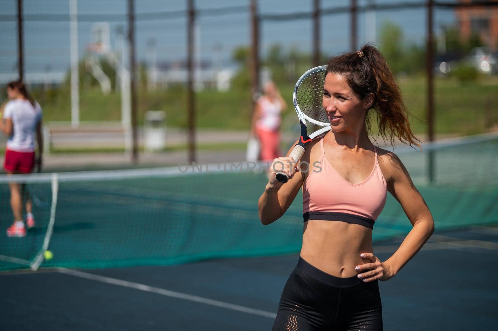 Beautiful European woman posing on a tennis court and holding a rocket.