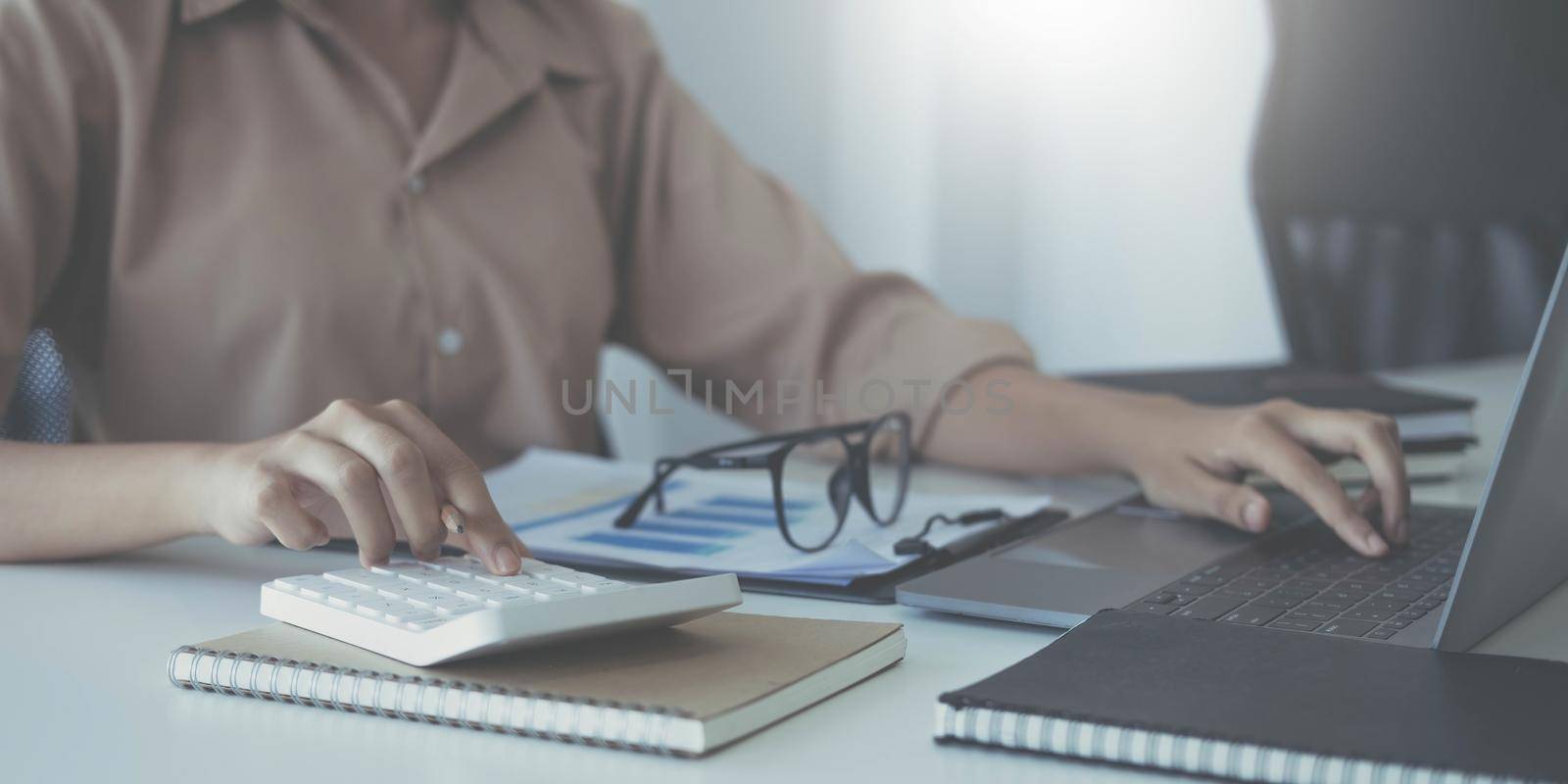 Business woman using calculator for do math finance on wooden desk in office and business working background, tax, accounting, statistics and analytic research concept.