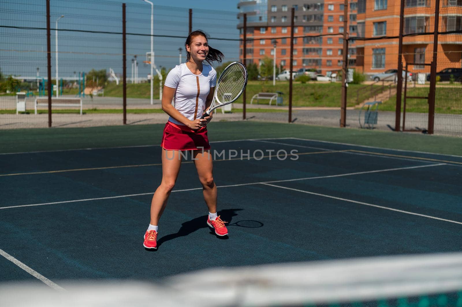 Young caucasian woman playing tennis on an outdoor court on a hot summer day