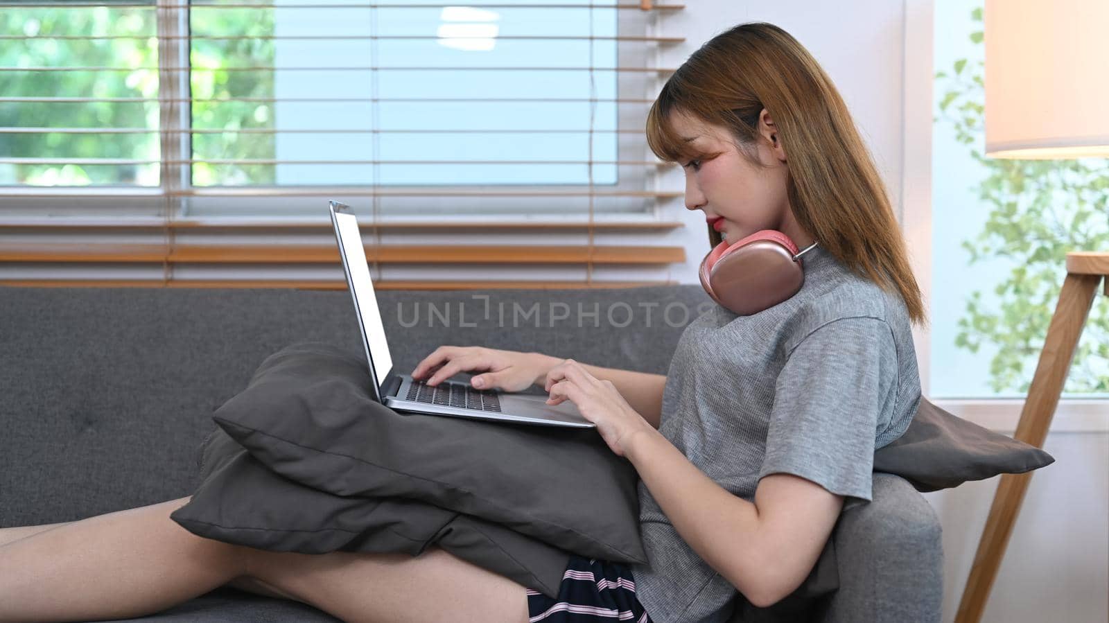 Young woman in casual clothes ordering food online or surfing internet on laptop at home.