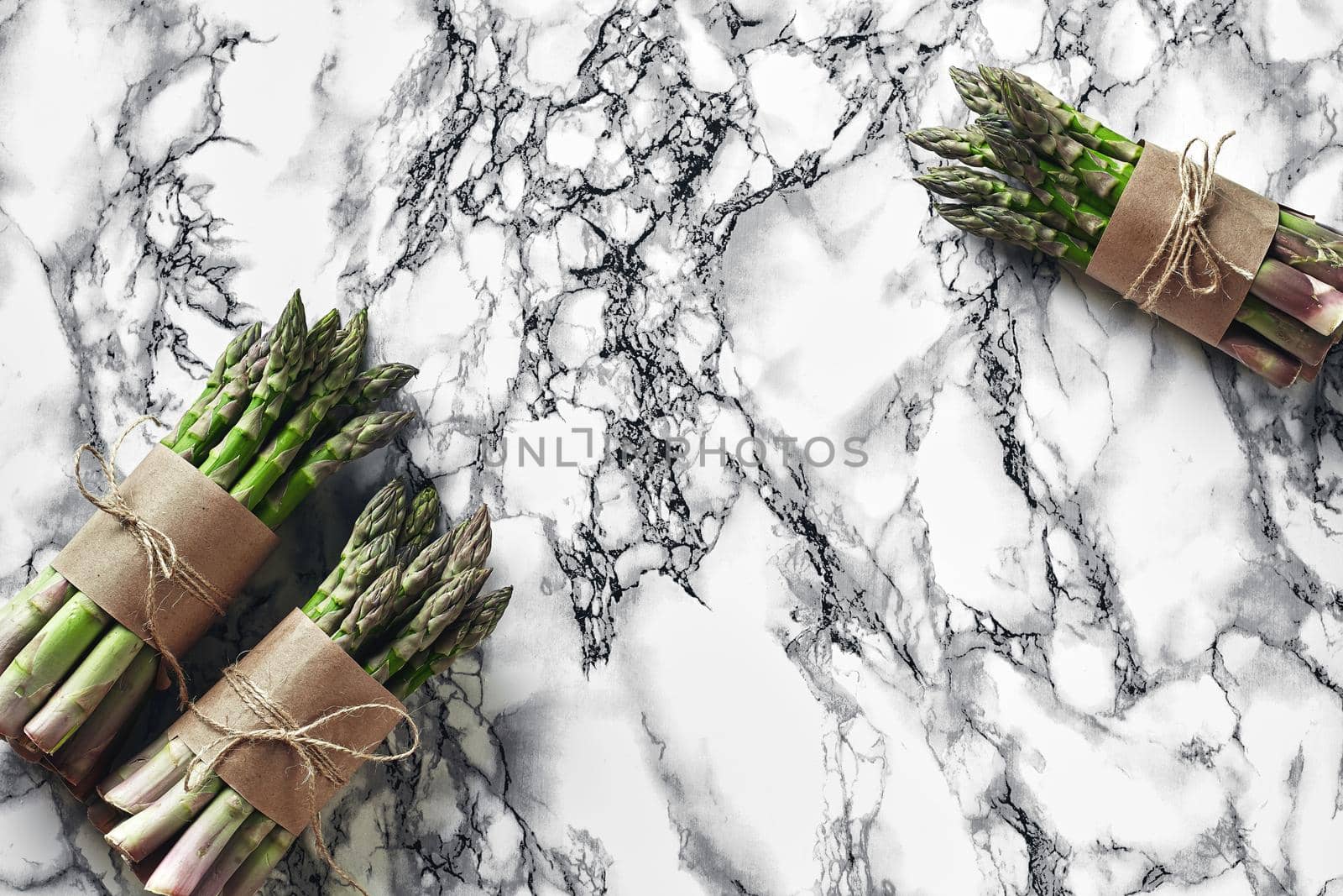 Bunch of an edible, juicy spears of asparagus on marble background. Fresh, green vegetables, top view. Healthy eating. Spring harvest, agricultural farming concept.