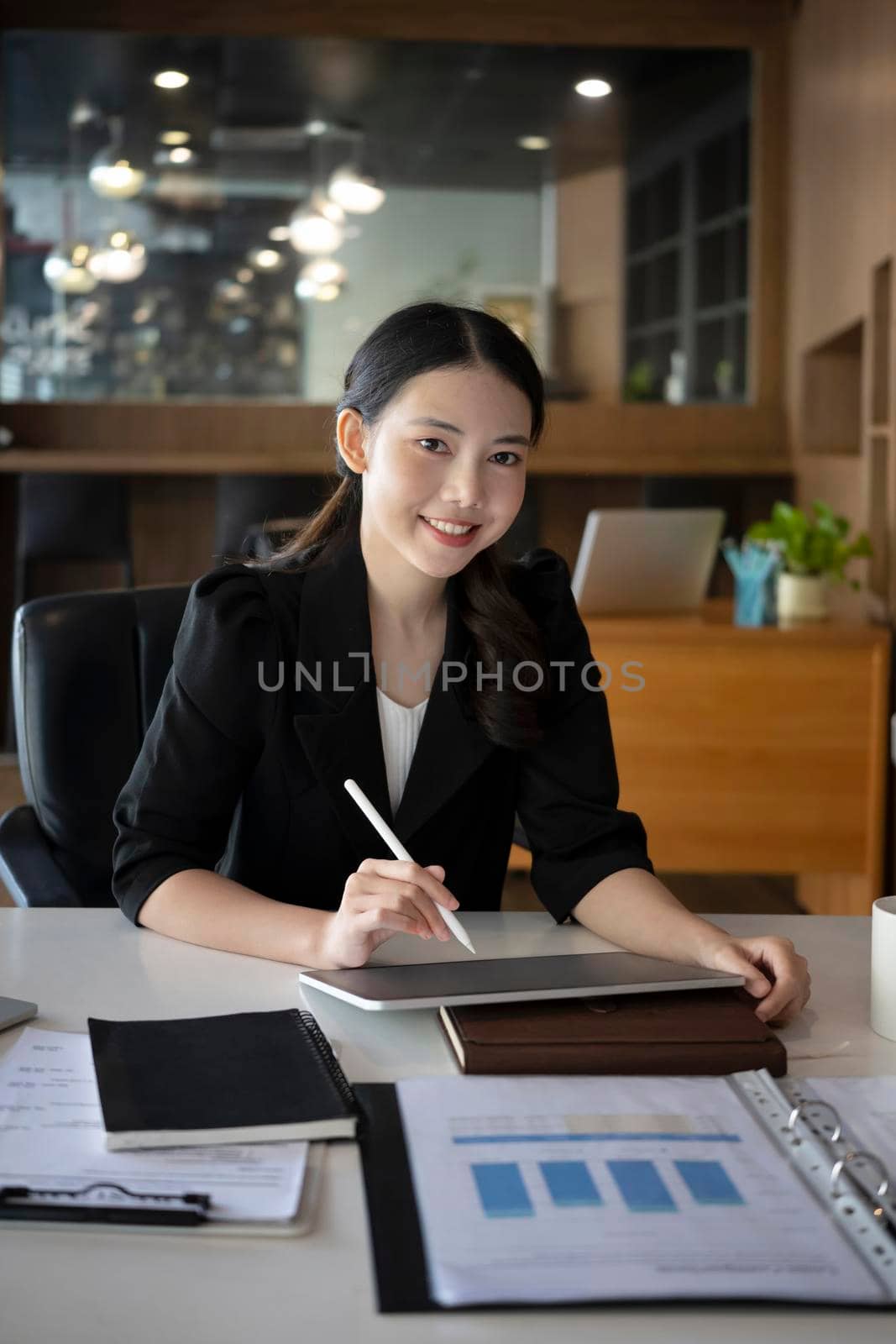 Portrait of confident businesswoman holding digital tablet and smiling to camera.