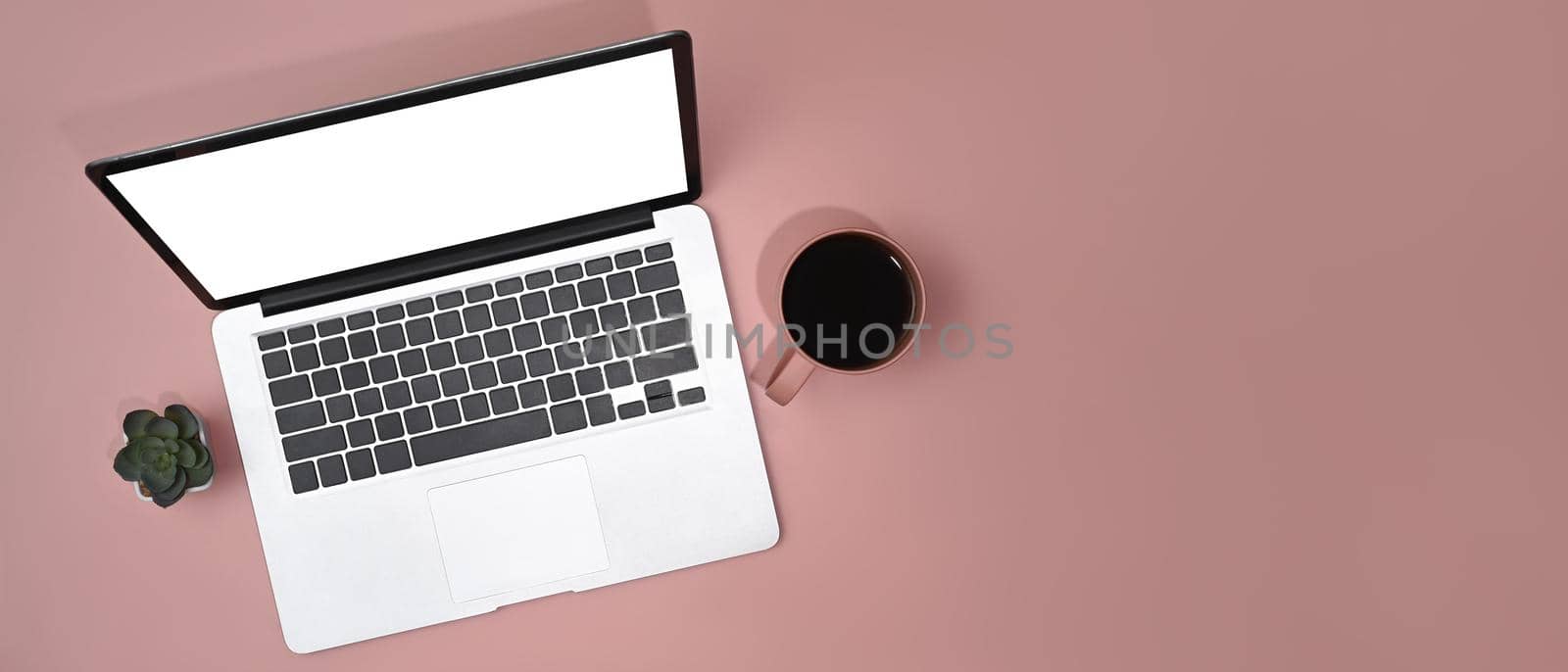 Mock up laptop computer with empty screen, coffee cup and succulent plant on pink background. Top view, Flat lay with copy space by prathanchorruangsak