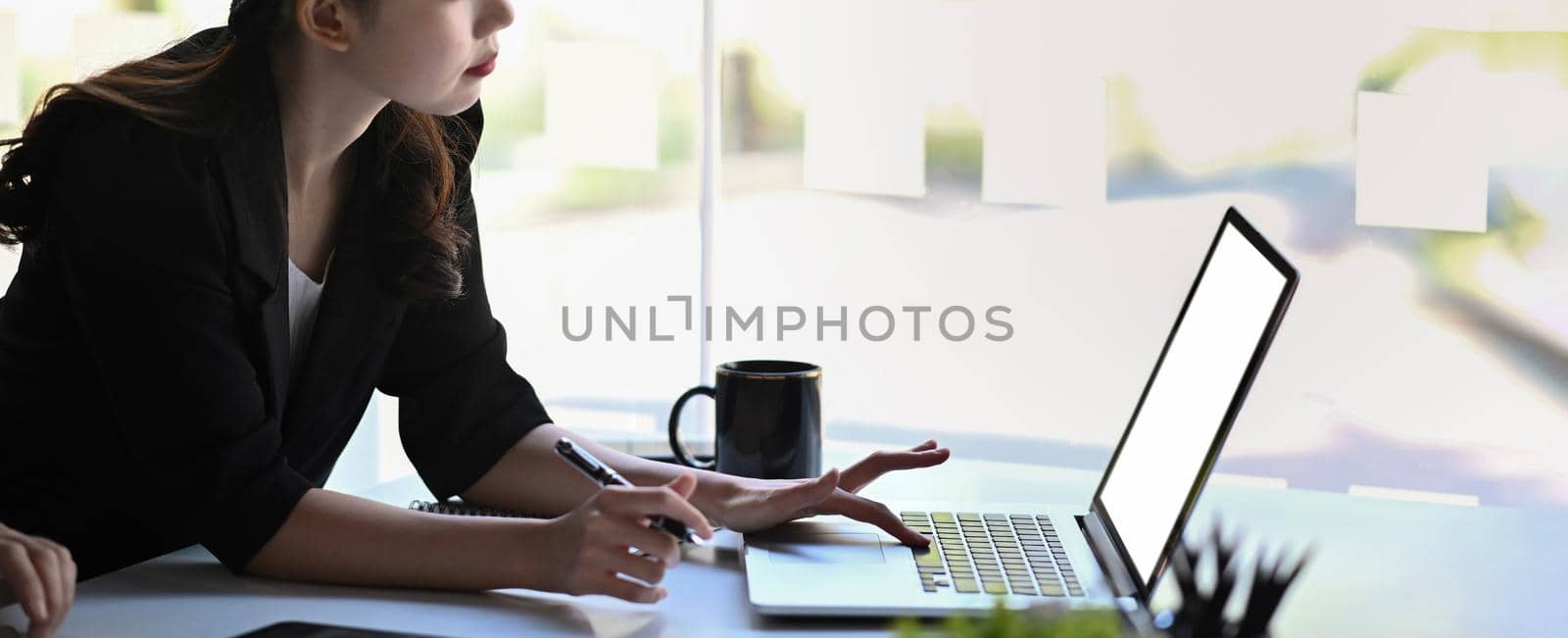 Businesswoman searching information with laptop computer at office desk.