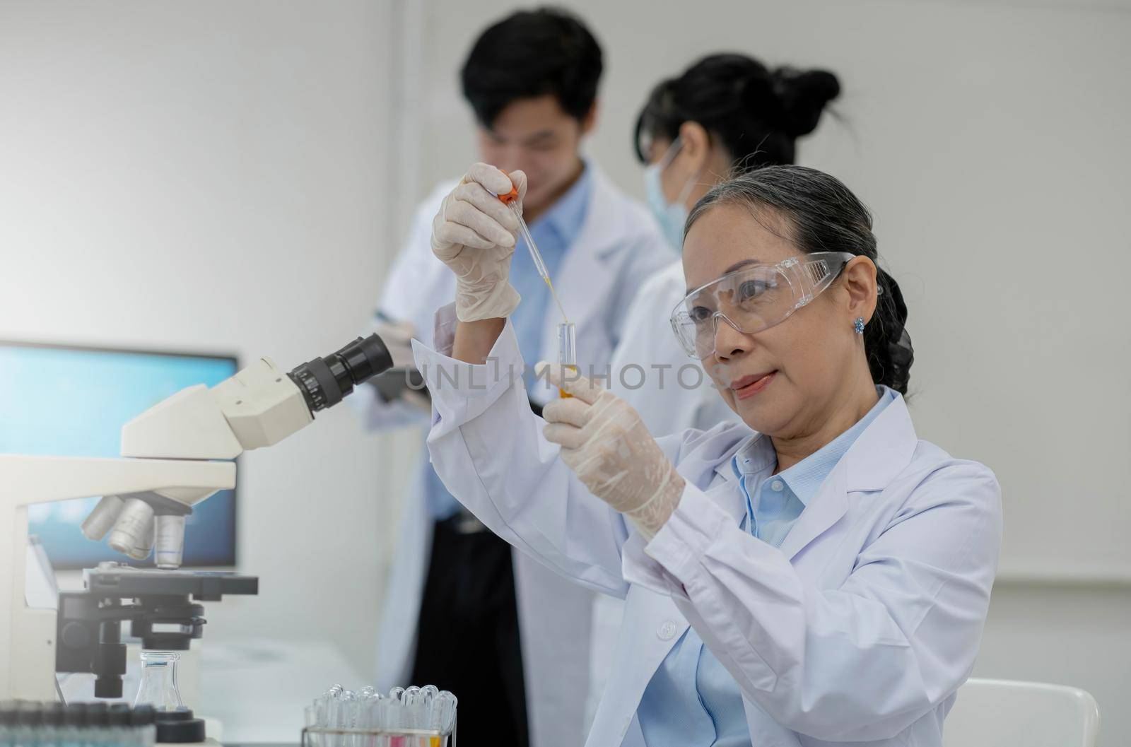 Health care researchers working in life science laboratory. Young female research scientist and senior male supervisor preparing and analyzing microscope slides in research lab..