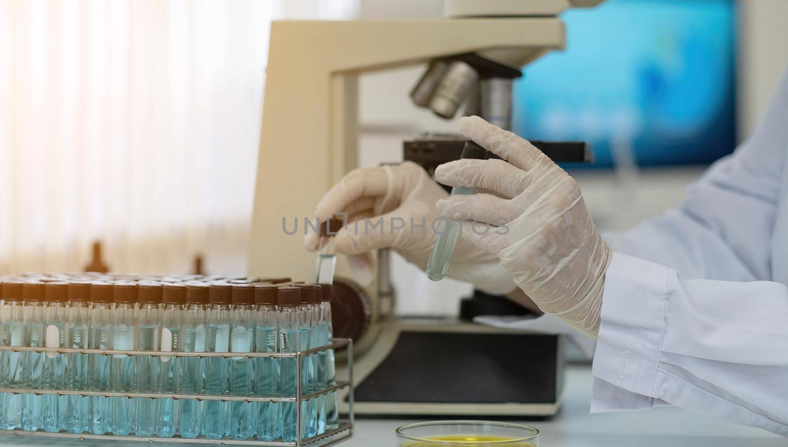 Biochemistry laboratory research, Chemist is analyzing sample in laboratory with Microscope equipment and science experiments glassware containing chemical liquid..