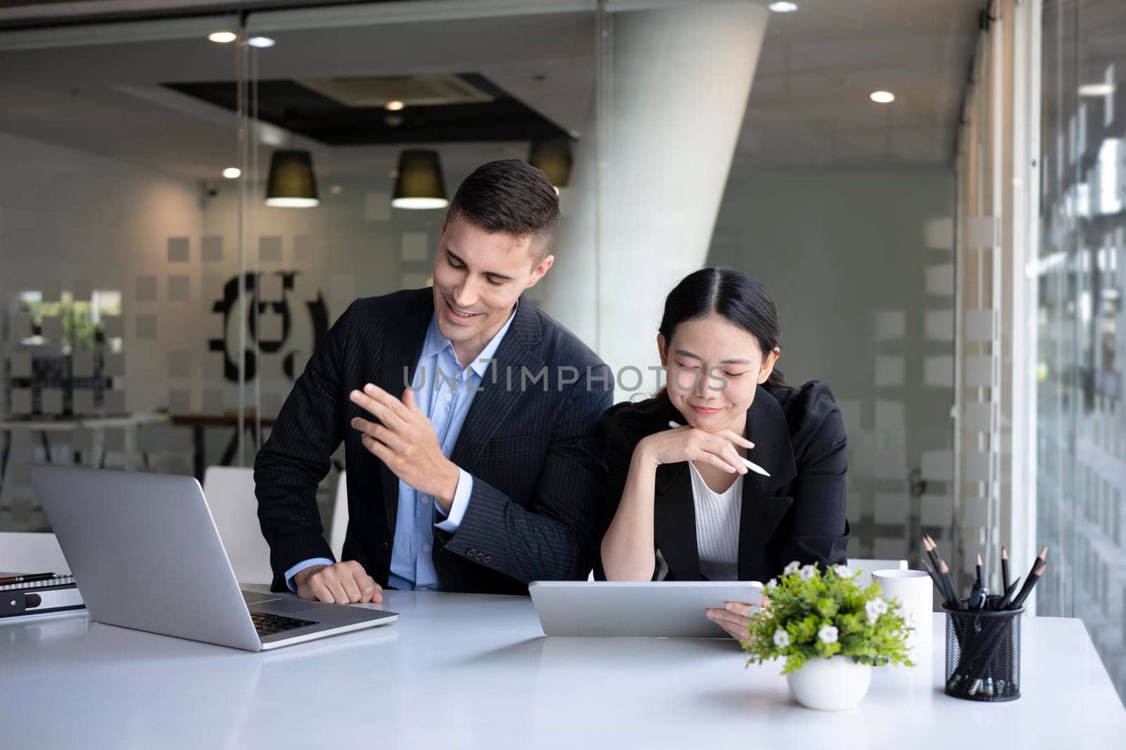 Two smiling business colleagues sitting in modern workplace and working together.