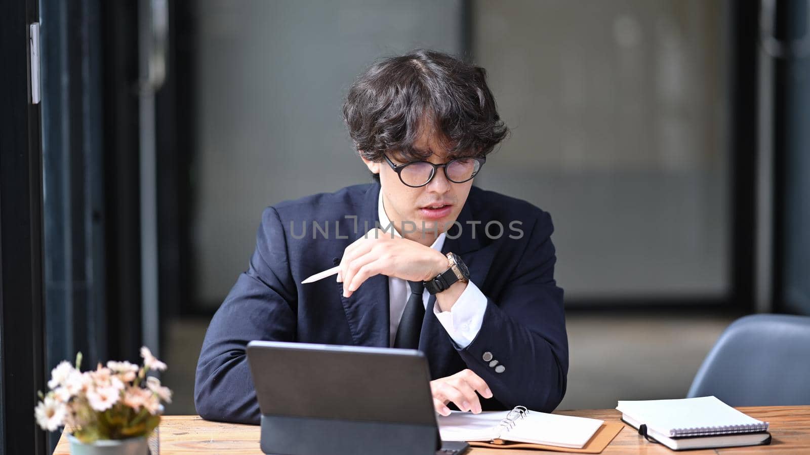 Young asian man in black suit working with computer tablet in office.