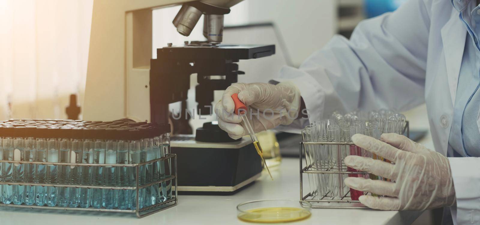 Closeup biochemistry laboratory research, Chemist is analyzing sample in laboratory with Microscope equipment and science experiments glassware containing chemical liquid. by wichayada