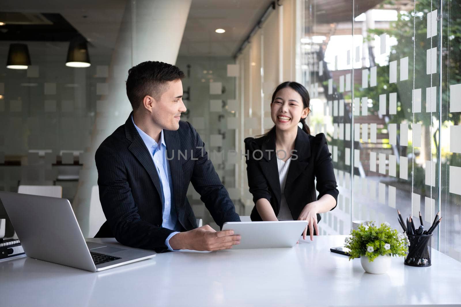 Cheerful businesswoman working on new project with her colleague in office.