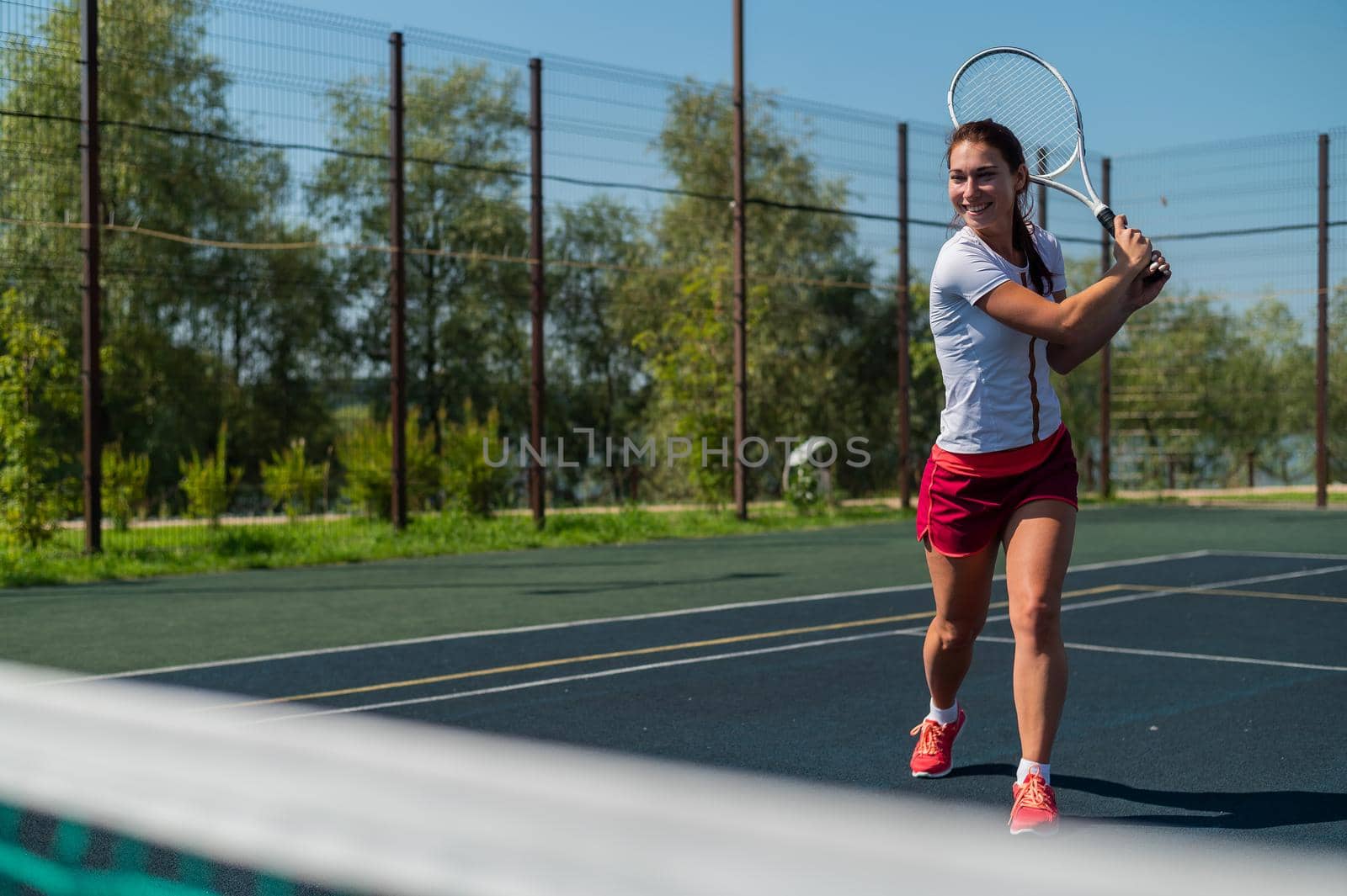 Young caucasian woman playing tennis on an outdoor court on a hot summer day. by mrwed54