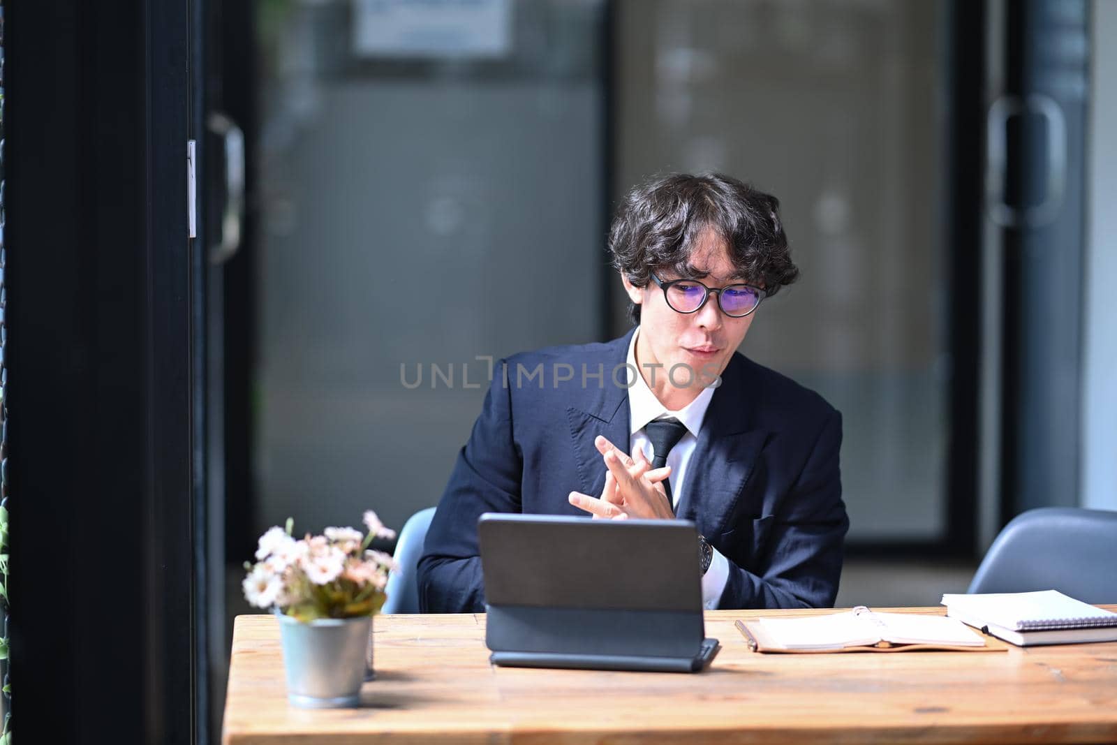 Young businessman working with computer tablet in modern workplace. by prathanchorruangsak