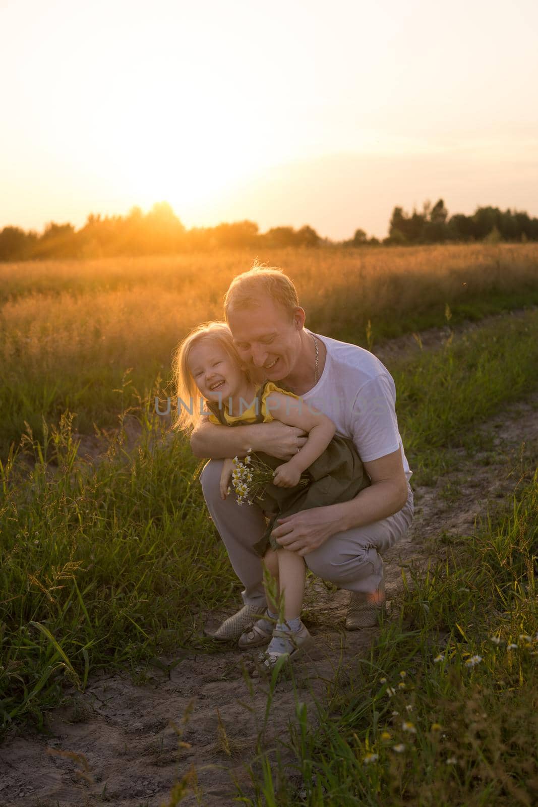 Dad and his blonde daughter are walking and having fun in a chamomile field. by Annu1tochka