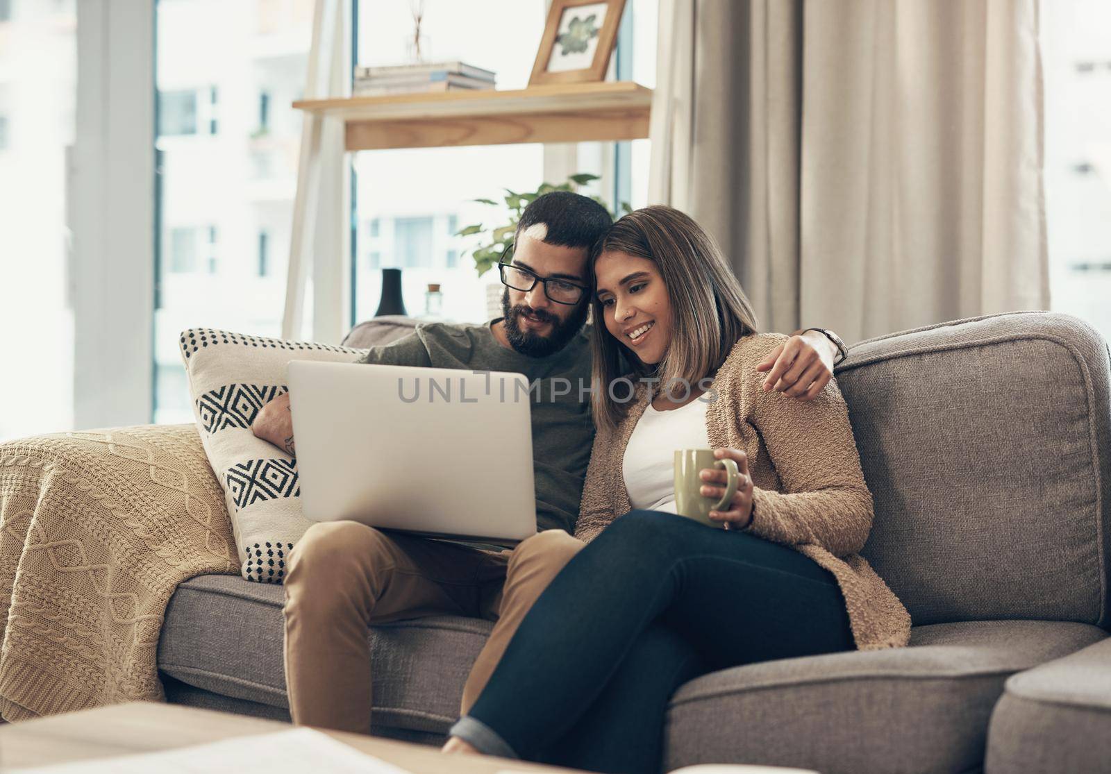 Nothing makes life more convenient than the net. a young couple using a laptop on the sofa at home. by YuriArcurs