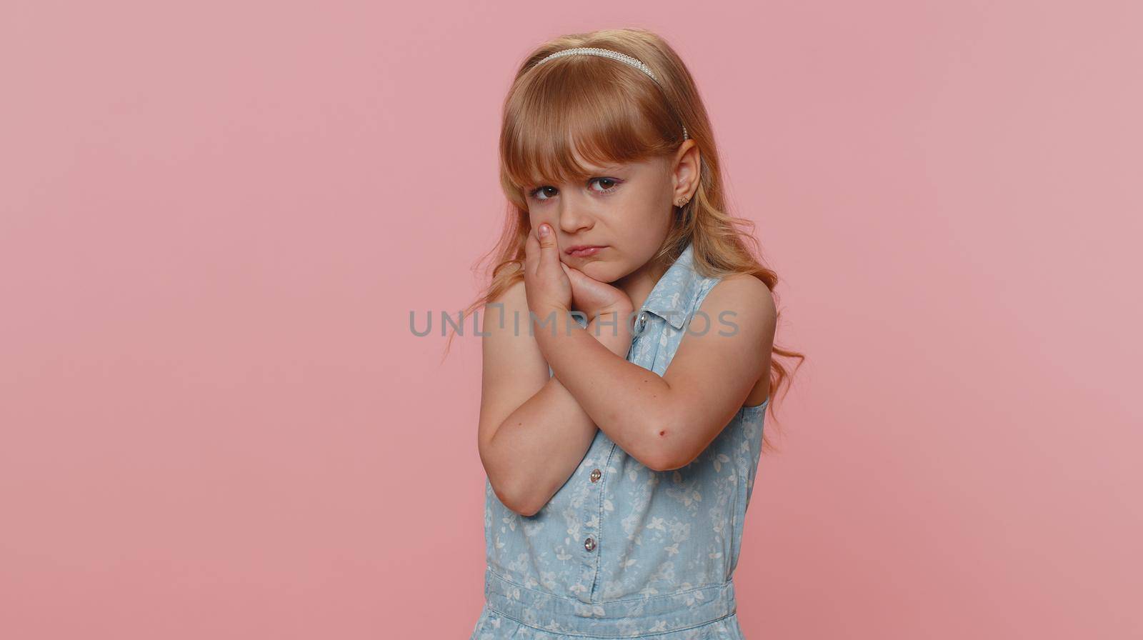 Dental problems. Young preteen child girl kid touching cheek, closing eyes with expression of terrible suffer from painful toothache, sensitive teeth, cavities. Toddler children on pink background