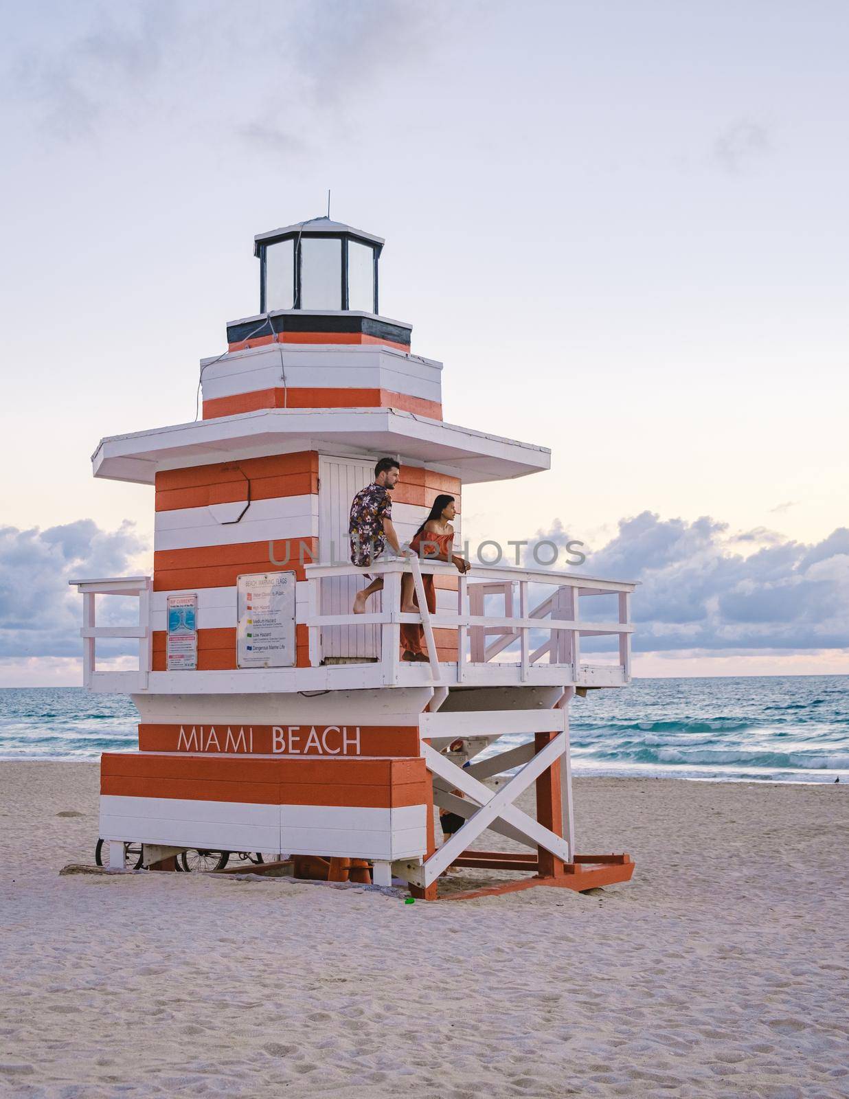 Miami Beach, a couple on the beach at Miami Florida, lifeguard hut Miami Asian women and caucasian men on the beach during sunset