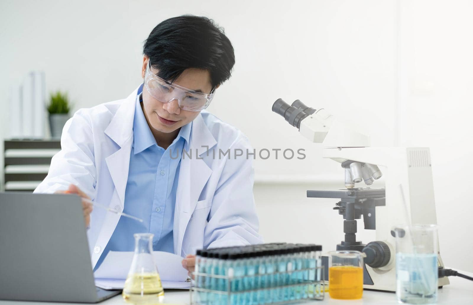 Medical Research Laboratory: Portrait of a Handsome Male Scientist Using Digital Tablet Computer, Analysing Liquid Biochemicals in a Laboratory Flask. by wichayada