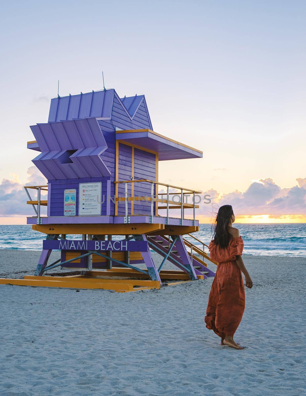 Miami Beach, a couple on the beach at Miami Florida, lifeguard hut Miami Asian women and caucasian men on the beach during sunset. Woman watching sunset on the beach